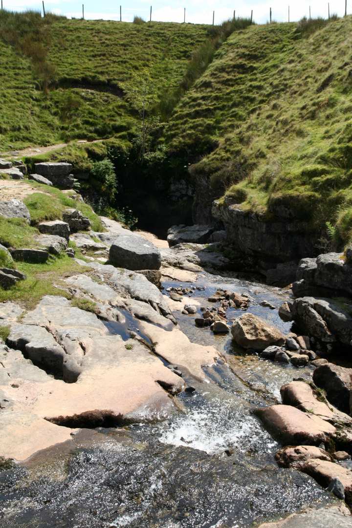 Water runs into a dark hole in the ground at Gaping Gill, a famous natural wonder in Yorkshire.